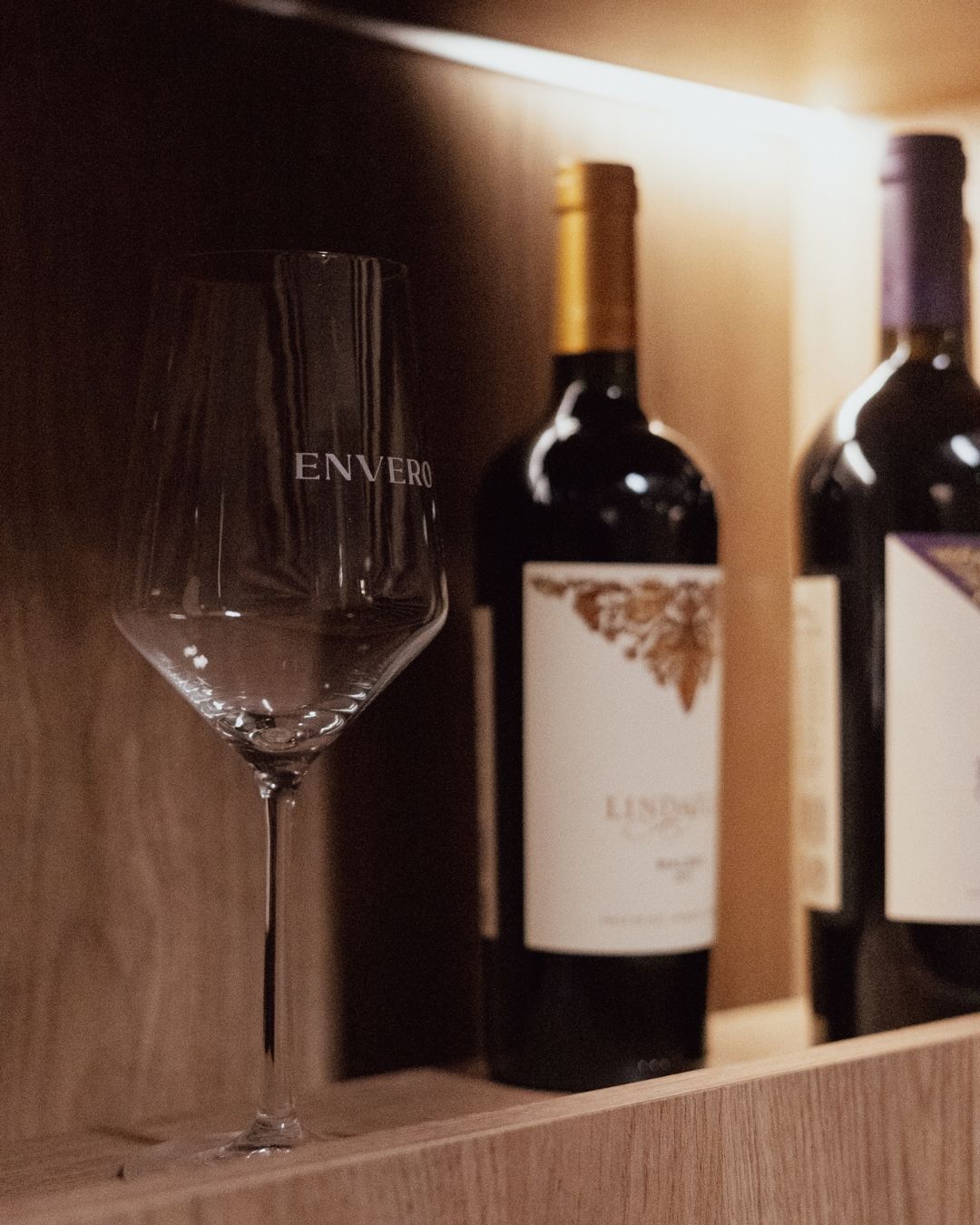 Botella de vino y copa sobre mesa de madera en Envero Club de Vinos, Santa Fe